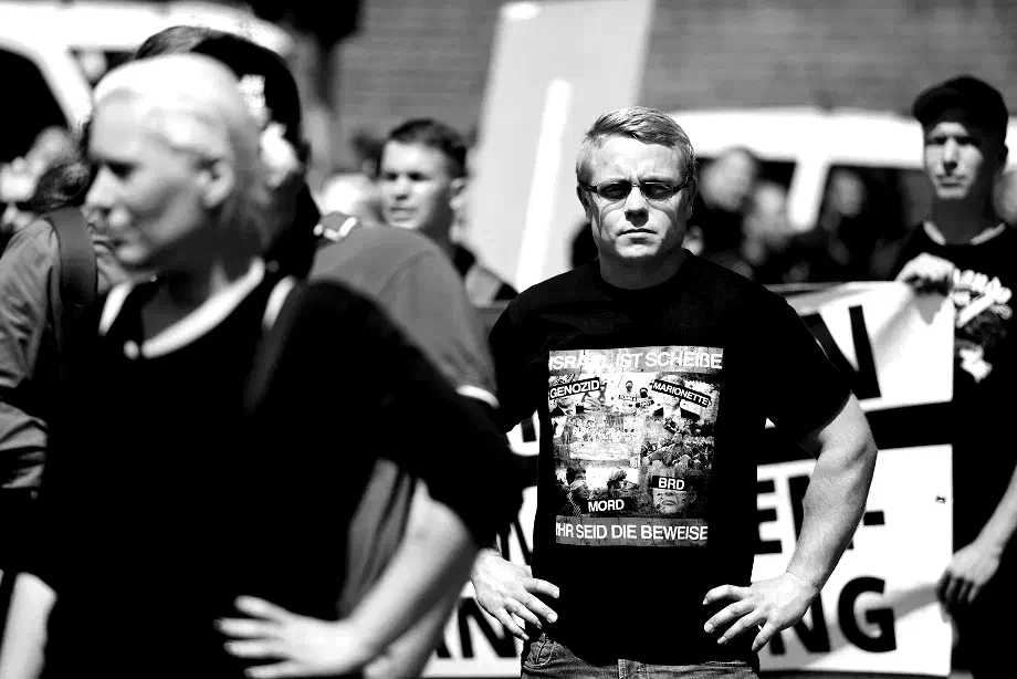Ebenfalls 2012 wurden in Nordrhein-Westfalen mehrere rechte Gruppen verboten: die Kameradschaften in Hamm, Aachen und Wuppertal sowie der Nationale Widerstand Dortmund (NWDO). In allen 4 Städten wurde kurz darauf Nachfolgeorganisationen gegründet, in Hamm und Dortmund als Kreisverbände der Partei "Die Rechte". Mitglieder aller vier verbotenen Gruppen waren und sind beim Tddz vertreten: als Teilnehmer*innen, Redner oder Organisatoren. Christoph Drewer, hier in Neuruppin, war 2018 zeitweilig Bundesvorsitzender der Partei