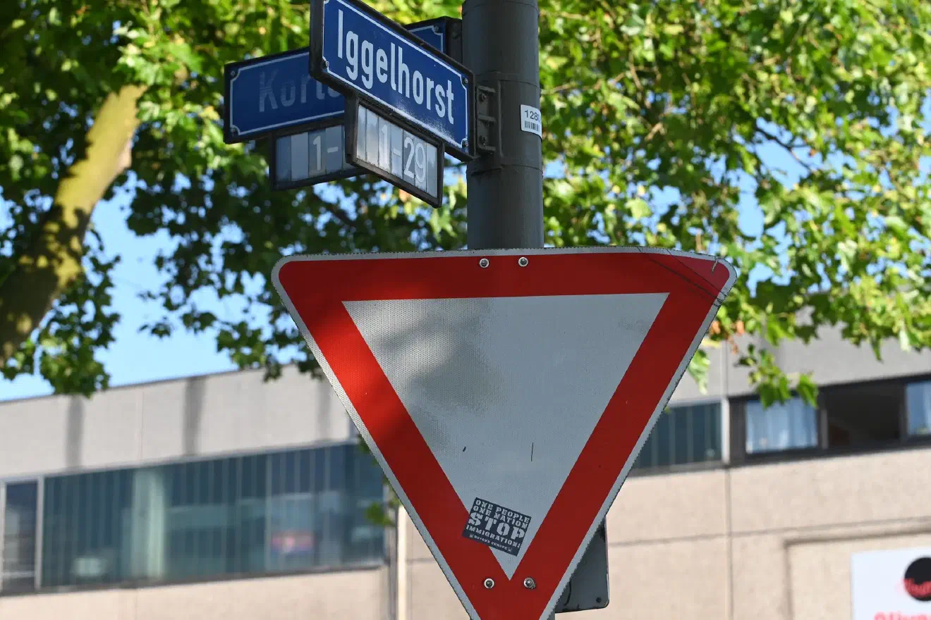 Am Straßenschild findet sich ein menschenverachtender Sticker aus dem Sortiment des  Neonazi-Versandhandels von Tommy Frenck.